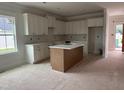 Bright kitchen featuring white cabinetry, center island, and abundant natural light at 163 Noramac Ct, Selma, NC 27576