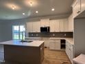 Modern white kitchen with stainless steel appliances, an island, and a stylish brick backsplash at 163 Noramac Ct, Selma, NC 27576