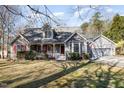 Charming gray home featuring red shutters, a covered porch, a two-car garage, and a well maintained lawn at 212 Wintergreen Dr, Garner, NC 27529