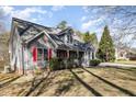 Charming gray home featuring red shutters, a covered porch, a two-car garage, and a well-manicured front lawn at 212 Wintergreen Dr, Garner, NC 27529