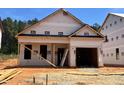 Exterior view of a new construction home with a visible garage and a door leaning against the side, set against a clear blue sky at 346 Bluejay St, Clayton, NC 27520