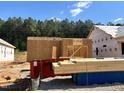 New construction of home featuring stacked lumber and framing materials in a wooded community at 354 Bluejay St, Clayton, NC 27520