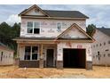 New construction two-story home featuring a covered entry, garage, and brick accents on the front facade at 354 Bluejay St, Clayton, NC 27520