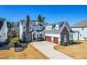 Expansive aerial view of two-story home with stone accents, three-car garage, manicured lawn, and a covered front porch at 3847 Stoneridge Forest Dr, Raleigh, NC 27612