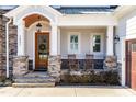 Inviting covered front porch with rocking chairs, stone accents, and wood door with wreath, exuding curb appeal at 3847 Stoneridge Forest Dr, Raleigh, NC 27612