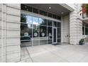Modern condominium entrance with glass doors, a stone facade, and exterior lighting fixtures at 400 W North St # 1204, Raleigh, NC 27603