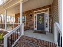 Cozy front porch featuring stone accents, rocking chairs, and a decorative front door at 424 Hocutt Farm Dr, Clayton, NC 27527