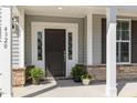 Close-up of the front door entrance, accentuated with decorative sidelights, brick accents, and potted plants at 4320 Stony Falls Way, Knightdale, NC 27545