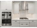 Modern kitchen with stainless steel double ovens, gas cooktop, custom range hood, and subway tile backsplash at 4320 Stony Falls Way, Knightdale, NC 27545