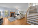 Bright living room featuring hardwood floors, fireplace, stairs, and large windows provide a cozy, inviting space at 445 S Greensboro St, Carrboro, NC 27510