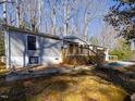 View of the home with a rear wood deck, trimmed yard and mature trees surrounding the property at 471 Deer Run, Pittsboro, NC 27312