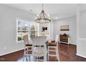 Bright dining area featuring a wood-trimmed window, chandelier and refinished white chairs around a table at 6817 Osprey Landing Dr, Wendell, NC 27591