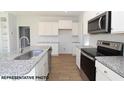 Modern kitchen featuring white cabinets, granite countertops, stainless steel appliances, and hardwood floors at 87 Legolas Ct, Middlesex, NC 27557
