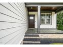Inviting front porch with stone accents, decorative pillars, and a dark-stained wood door and adjacent window at 913 Clayton Rd, Angier, NC 27501