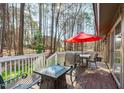 Outdoor wooden deck with table, chairs, fire pit, and red umbrella surrounded by a wooded backyard at 11808 Black Horse Run, Raleigh, NC 27613