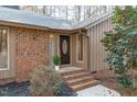 Inviting brick entryway with a classic wood door, enhanced by manicured landscaping and warm exterior lighting at 11808 Black Horse Run, Raleigh, NC 27613