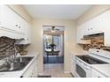 Functional kitchen with white cabinets, tile backsplash, and appliances next to the light-filled dining area at 1245 Schaub Dr, Raleigh, NC 27606