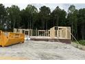 New home construction with wooden frame and brick foundation set against a backdrop of lush trees at 129 Tigris Ct, Zebulon, NC 27597