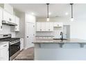 Well-equipped kitchen with stainless steel appliances, white cabinets, a gray backsplash, and an island at 129 Tigris Ct, Zebulon, NC 27597