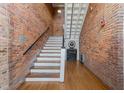 Unique staircase with exposed brick walls and hardwood flooring creates a historic aesthetic at 1535 Caraleigh Mills Ct # 105, Raleigh, NC 27603