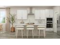 Modern kitchen with white cabinets, stainless steel appliances, large island with bar seating, and stylish decor at 1573 Goldfinch Perch Ln, Knightdale, NC 27545