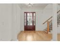 Bright foyer featuring hardwood floors, a staircase, and a glass-paneled front door providing natural light at 162 Arabella Ct, Cary, NC 27518
