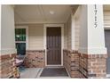 Charming front porch featuring brick accents, a brown door, and a welcoming entryway at 1715 Capstone Dr, Durham, NC 27713