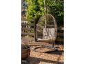 A cozy hanging chair in backyard offers a relaxing spot near fire pit and wooden fence at 202 High St, Carrboro, NC 27510