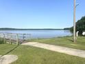 Scenic lake view with a wooden dock and walkway surrounded by lush greenery on a clear, sunny day at 207 N Movado Trl, Kenly, NC 27542