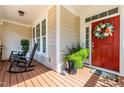 Cozy front porch with rocking chairs and a festive wreath on the red front door at 2739 Elderberry Ln, Apex, NC 27539