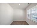 Minimalist-style room with wood-look floors, bright window, and white walls at 291 Hanging Elm Ln, Fuquay Varina, NC 27526