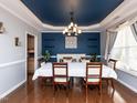 Elegant dining room with a unique blue ceiling, a modern chandelier, and a large table for entertaining at 3059 Hyco Lake Ct, Fuquay Varina, NC 27526