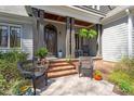 Inviting front porch featuring chairs, stone pavers, brick steps, and decorative plants at 3120 A Timberlyne Dr, Mebane, NC 27302