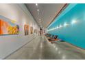 Long gallery hallway features concrete floors, track lighting, and colorful artwork at 319 Fayetteville St # 207, Raleigh, NC 27601