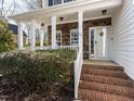 Inviting front porch with brick steps, stone accents and white pillars creating a welcoming entry at 543 Chatham Forest Dr, Pittsboro, NC 27312