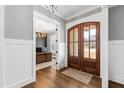 Elegant entryway with a beautiful wood door, wainscoting, and a view into a stylish home office at 6108 Norwood Place Ct, Raleigh, NC 27613