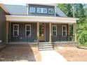 Inviting front porch with stone steps, wooden pillars, iron railings and a stylish entrance door at 65 Stream View Way, Spring Hope, NC 27882