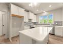 Bright kitchen with white cabinets, stainless appliances, an island, and neutral backsplash tile at 65 Stream View Way, Spring Hope, NC 27882