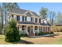Beautiful brick home with a covered front porch, black shutters, and lush green landscaping at 706 Oldwyck Dr, Fuquay Varina, NC 27526