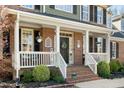 Inviting front porch with brick accents, white railings, and decorative hanging plants at 706 Oldwyck Dr, Fuquay Varina, NC 27526