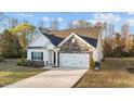 Inviting single-Gathering home with stone and vinyl siding, a two-car garage, and a well-manicured front lawn at 75 Red Crabapple Ct, Clayton, NC 27520