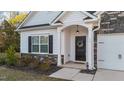 Close-up of front porch featuring a black door with a wreath, stone accents, and well-maintained landscaping at 75 Red Crabapple Ct, Clayton, NC 27520