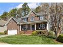 Charming two-story brick home with a well-manicured front lawn and covered porch at 8215 Cushing St, Raleigh, NC 27613