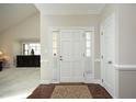 Bright and inviting foyer features a white door and decorative rug over hardwood flooring at 8310 Wycombe Ln, Raleigh, NC 27615
