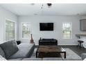 Cozy living room with dark floors, a guitar, modern media console, and large windows at 105 Village Dr, Broadway, NC 27505