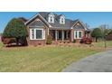Inviting brick house with dormer windows, manicured lawn, and charming landscaping at 1055 Tilghman Rd, Dunn, NC 28334