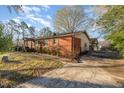 Brick exterior with a concrete driveway and mature landscaping, showing the side of the property at 1122 Snow Hill Rd, Durham, NC 27712