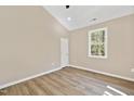 Neutral bedroom featuring wood-look flooring, a large window, and recessed lighting at 133 Mohawk Dr, Louisburg, NC 27549