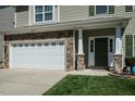 Close-up of a charming home showcasing a stone accent garage, and a well-manicured front lawn at 1403 Copper Cir, Mebane, NC 27302