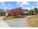 Brick home with inviting porch and a colorful flowering tree, complemented by a gravel driveway at 3030 Old Stage S Rd, Erwin, NC 28339